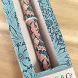 Two floral-patterned pens in a decorative box on a wooden surface