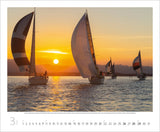 A photo of sailing boats on still water with a sunset.