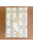 White towel with gold and green leaf pattern on a brown background