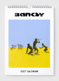 2027 calendar with artwork by Banksy featuring three figures and shopping carts on a blue and yellow background.