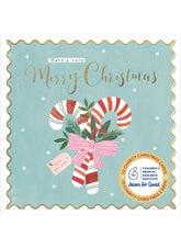 A square Christmas card with scalloped edges on a white background. The card has a light blue background with gold foil-style text reading 'Have a very Merry Christmas,' white snowflakes, and an illustration of two striped candy canes tied with a pink bow, green leaves, and small red berries.