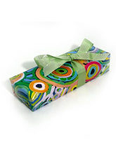 A rectangular gift box wrapped in vibrant, multicolored abstract patterned paper with a light green satin ribbon tied in a bow, set against a plain white background.