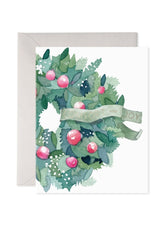 A wreath in greens and pink with a banner saying Comfort and Joy.