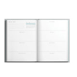Open planner with calendar and weekly layout on a white background