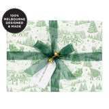 A gift wrapped in a green Christmas scene on white with a green ribbon.