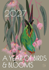 A square illustrated cover design featuring a green bird hanging among pink blossoms and long gray-green leaves on a taupe background, with the text '2027' at the top and 'A YEAR OF BIRDS & BLOOMS' at the bottom.