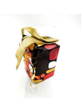 A small gift box wrapped in black paper with a bold red, orange, and white abstract pattern, tied with a shiny gold ribbon and bow on a white background.