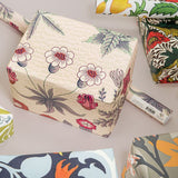 Floral-patterned gift box on a light gray surface with other patterned boxes in the background.