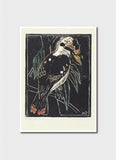 A card featuring a stylized bird illustration on a dark background, shown against a light gray wall. The print has a cream border and the artwork uses black, white, gray, green, orange, and red tones.