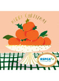 A festive Christmas card illustration featuring a pile of oranges on a pedestal plate with holly leaves, under the words 'MERRY CHRISTMAS.' The card has a peach background, a green-and-white plaid tablecloth, and an RSPCA logo badge at the bottom right.