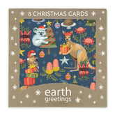 A square package of Earth Greetings Christmas cards featuring a festive illustrated design with a koala, kangaroo, bird, gifts, trees, and flowers on a dark blue background, surrounded by a tan border with white snowflake motifs and the text '8 CHRISTMAS CARDS' and 'earth greetings'.