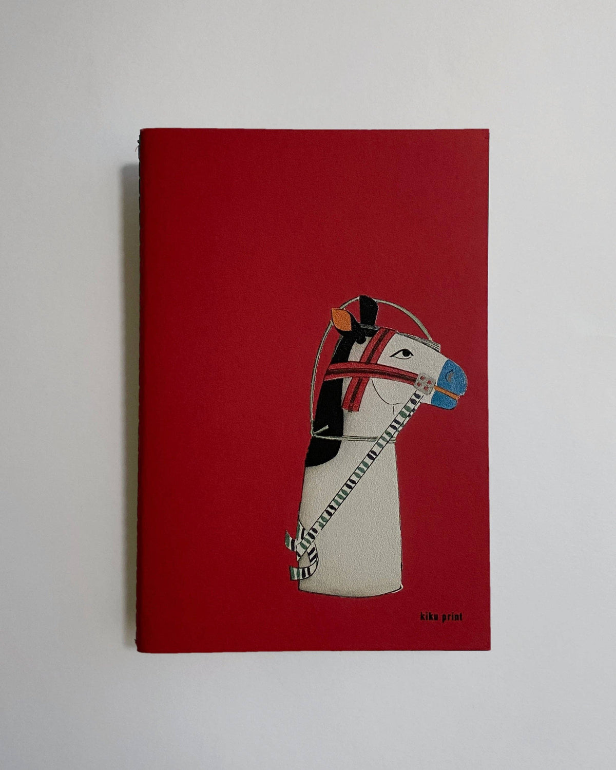 A red hardcover notebook or journal featuring a stylized illustration of a zebra wearing a helmet on the front cover, photographed against a plain light gray background.