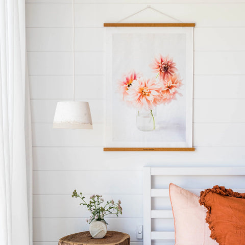 Floral artwork on a white wall with decorative pillows and a lamp in the foreground.