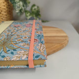 Floral notebook with pink ribbon on a white surface