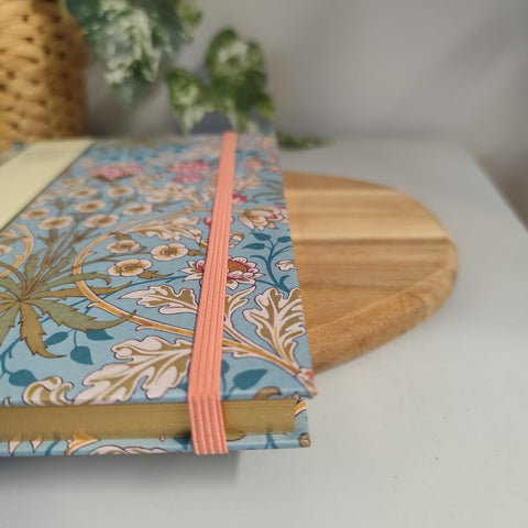 Floral notebook with pink ribbon on a white surface