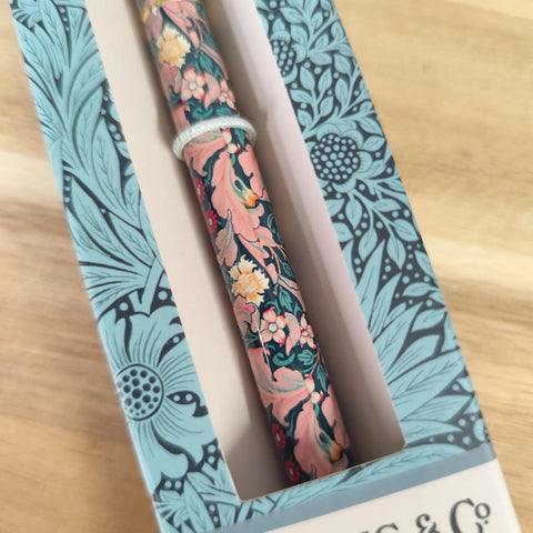 Two floral-patterned pens in a decorative box on a wooden surface