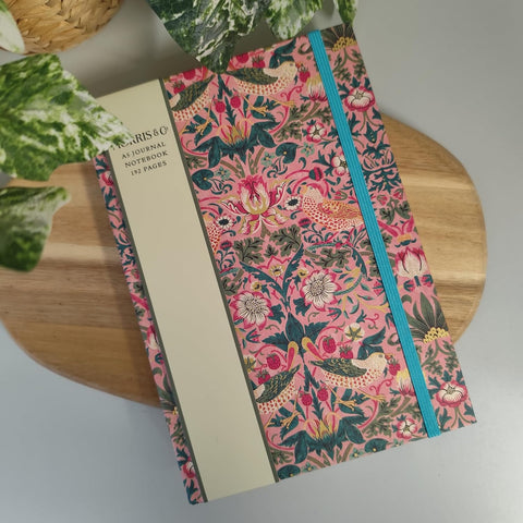 Floral notebook with a blue zipper on a wooden surface