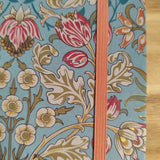 Floral patterned notebook with a pink ribbon on a wooden surface