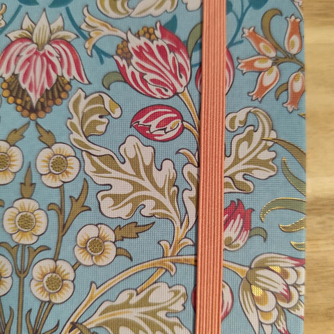 Floral patterned notebook with a pink ribbon on a wooden surface