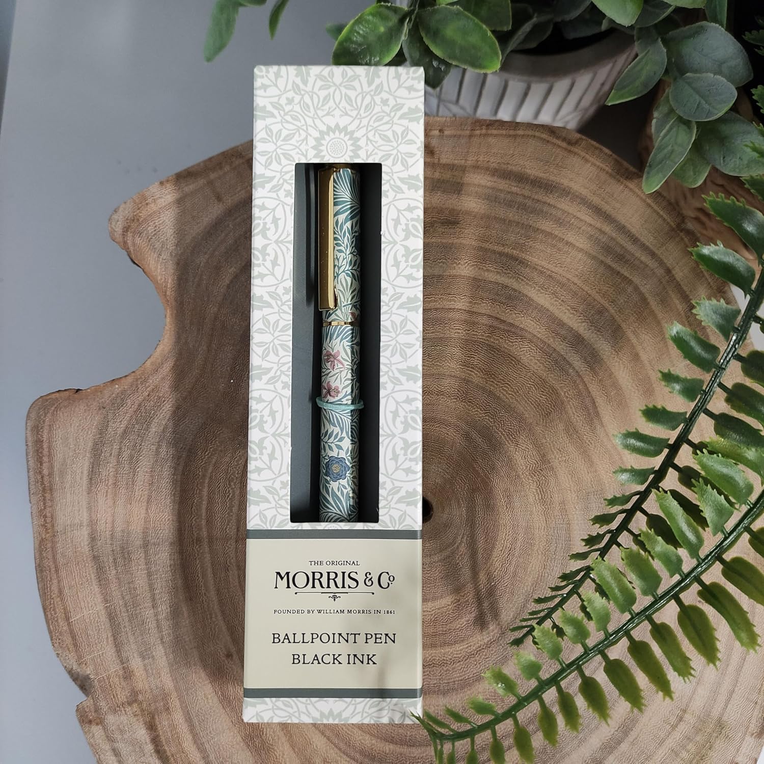 Ballpoint pen in packaging on a wooden surface with greenery
