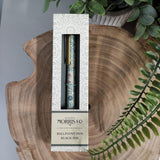 Ballpoint pen in packaging on a wooden surface with greenery