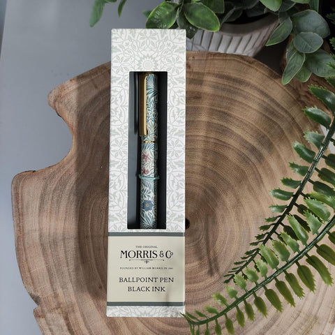 Ballpoint pen in packaging on a wooden surface with greenery
