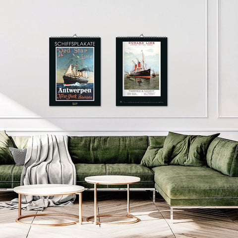 A room with green sofas with calendars on the wall.