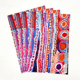 A fan of colorful patterned paper sheets with abstract hand-drawn designs in red, pink, blue, purple, orange, and white on a plain white background.