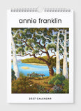 2027 calendar by Annie Franklin with a scenic design of trees and a lake.