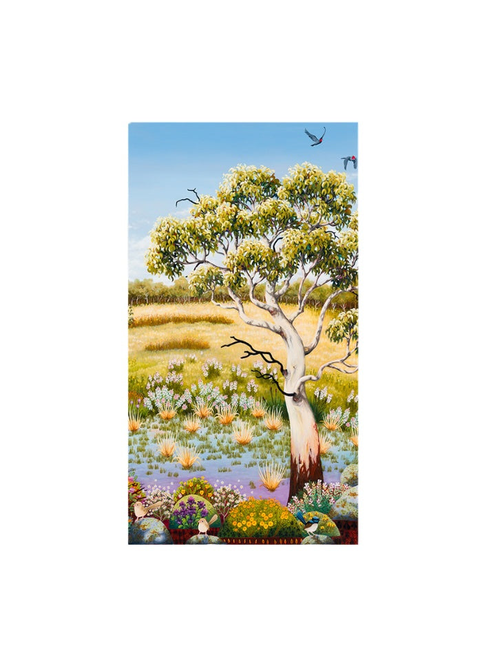 A tree with flowers and scrub on the ground and a blue sky with birds in the background.