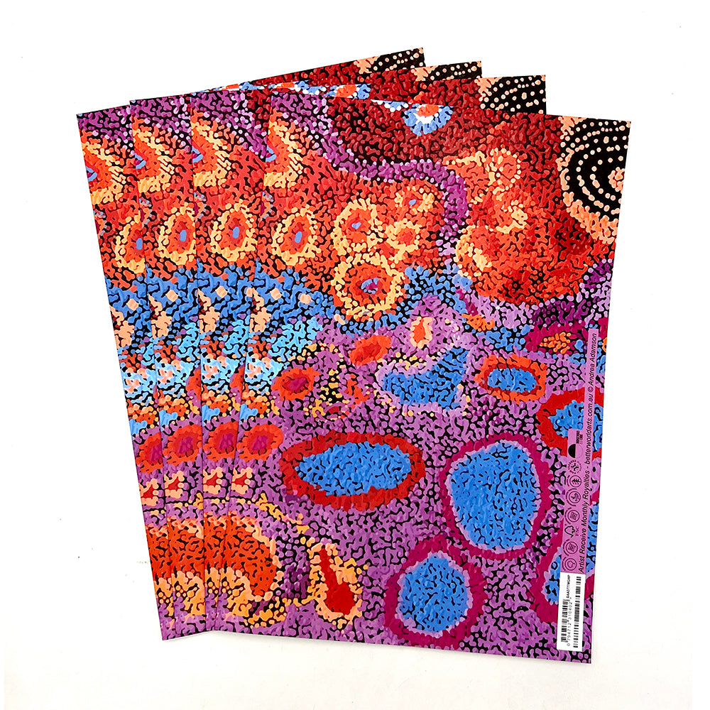 A stack of four folded sheets of wrapping paper featuring a vibrant Aboriginal dot art pattern with red, orange, blue, purple, and black dots on a white background.