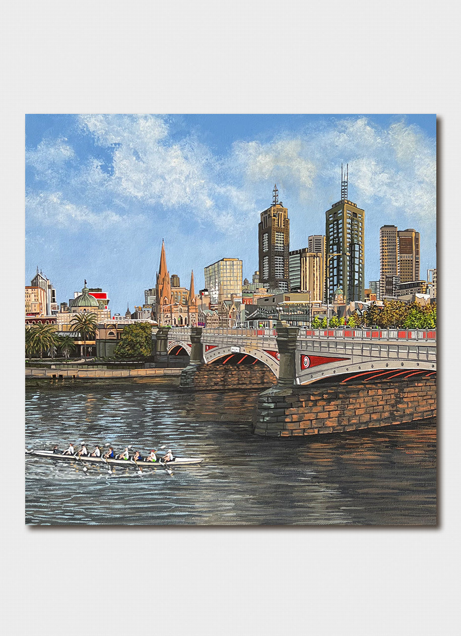 Rowers on a river under a cty bridge.