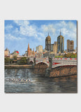 Rowers on a river under a cty bridge.