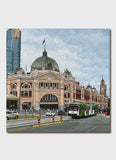 An old building on a major city corner with trams in front.