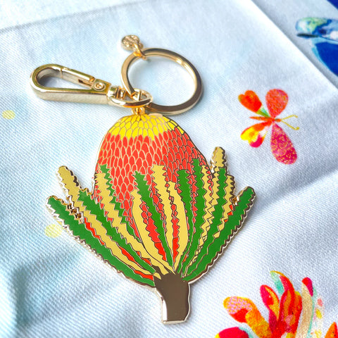 Keychain with a colorful plant design on a white fabric background with butterfly patterns.