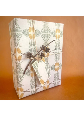 Gift box wrapped in decorative paper with a branch and tag on an orange background