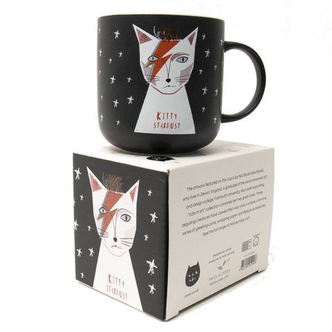 A black mug with white stars and a cat with  a lightning mark on its face says Kitty Stardust - art by Niaski.