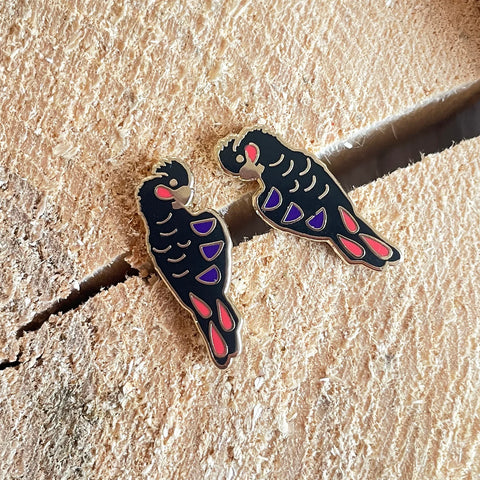 Two bird-shaped pins on a textured beige surface