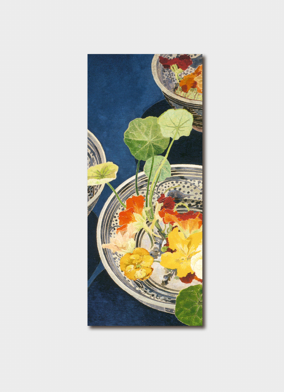 Yellow and orange nasturtiums flowers in a blue and white bowl on a navy background.