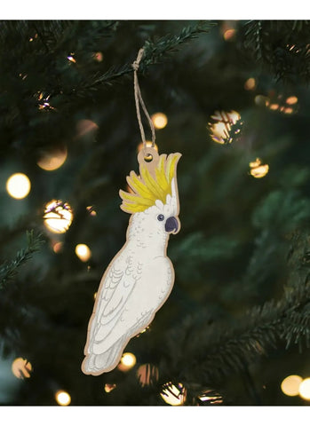 Decorative parrot ornament hanging on a Christmas tree with lights in the background