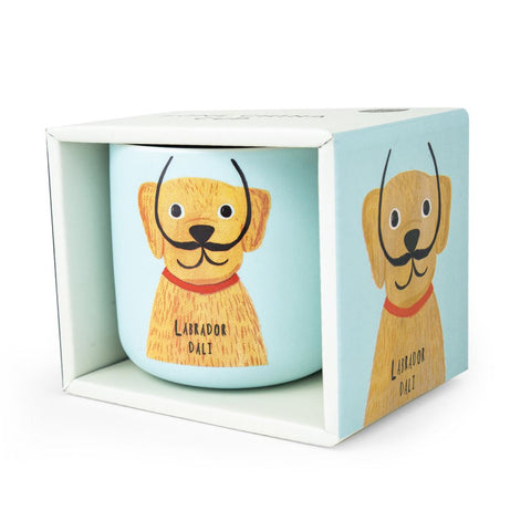 A pale blue mug with a dog with a moustache on it, in it's box. Labrador Dali by Niaski.