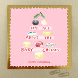 A square Christmas card with a pink background, gold frame and a tree shape made from cheeses.