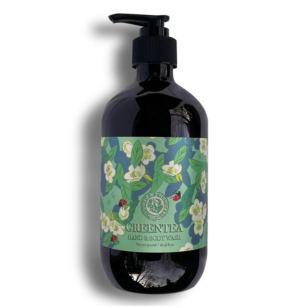A dark amber pump bottle of Green Tea Hand & Body Wash by The Body Shop, featuring a black pump and a green floral label with white tea blossoms and ladybugs.