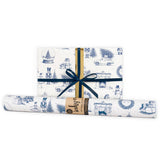 A wrapped gift next to a gift wrap roll in blue and white Christmas design.