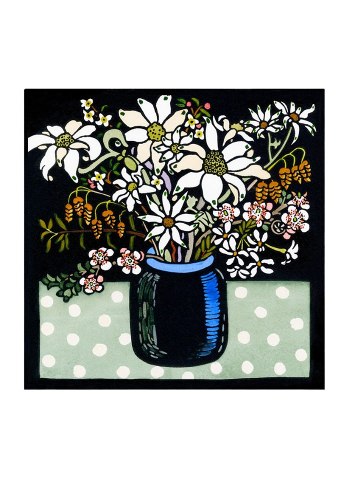 A square card with a vase of flannel flowers and other natives in a blue vase on a green and white spotted tablecloth