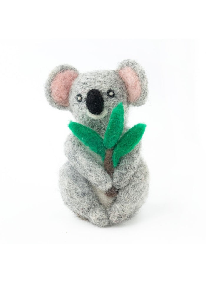 Felted toy koala holding a leaf on a white background