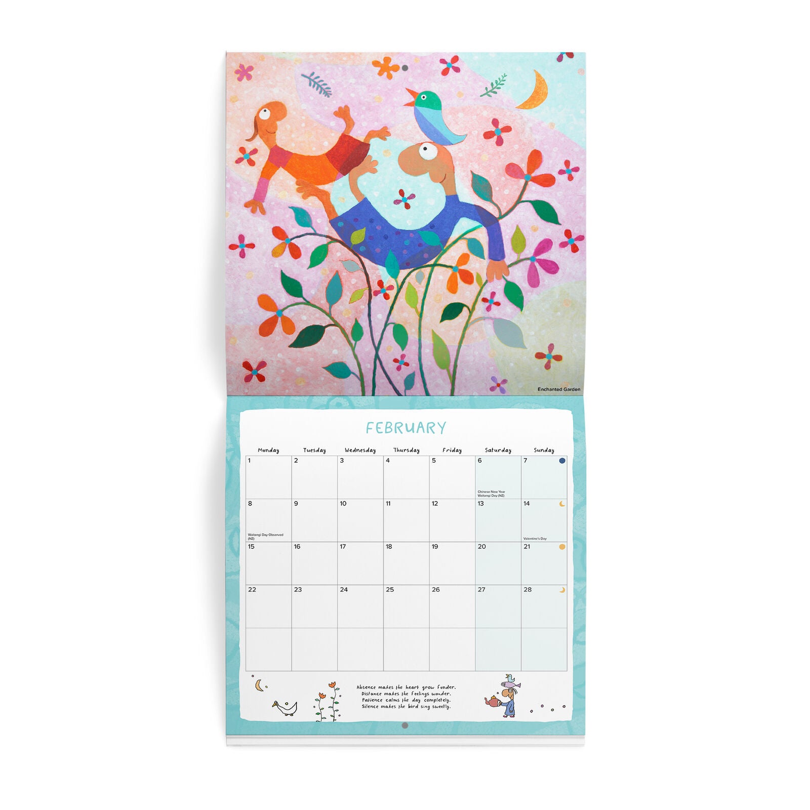 A hanging wall calendar shown open to the February page, featuring a colorful whimsical illustration on the cover with two birds, flowers, and a crescent moon above a monthly calendar grid.
