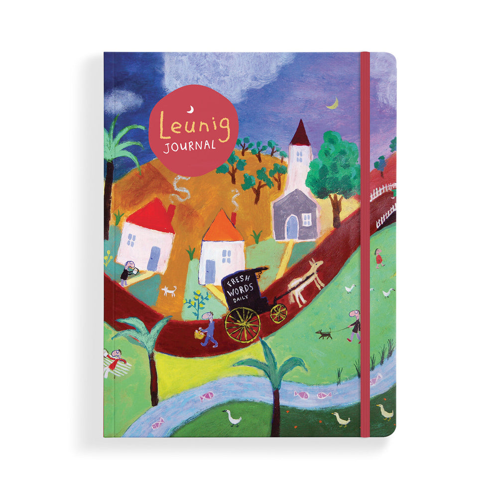 A hardcover Leunig Journal featuring a colorful, whimsical folk-art style illustration of a village scene with houses, trees, a river, and a red elastic closure band.