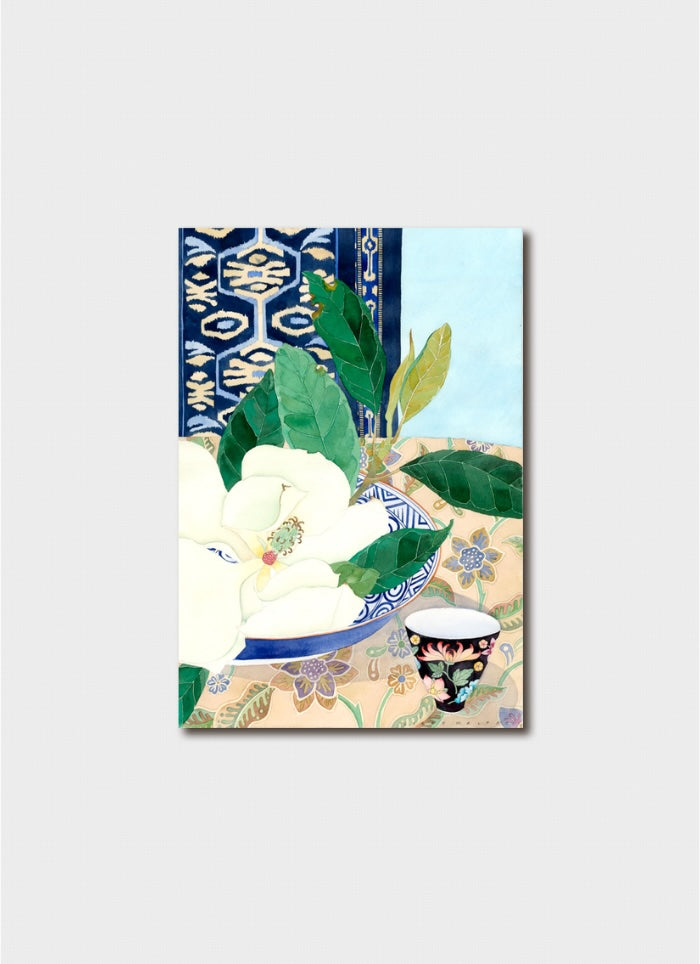 White magnolisa in a bowl next to a floral teacup with a patterned background.