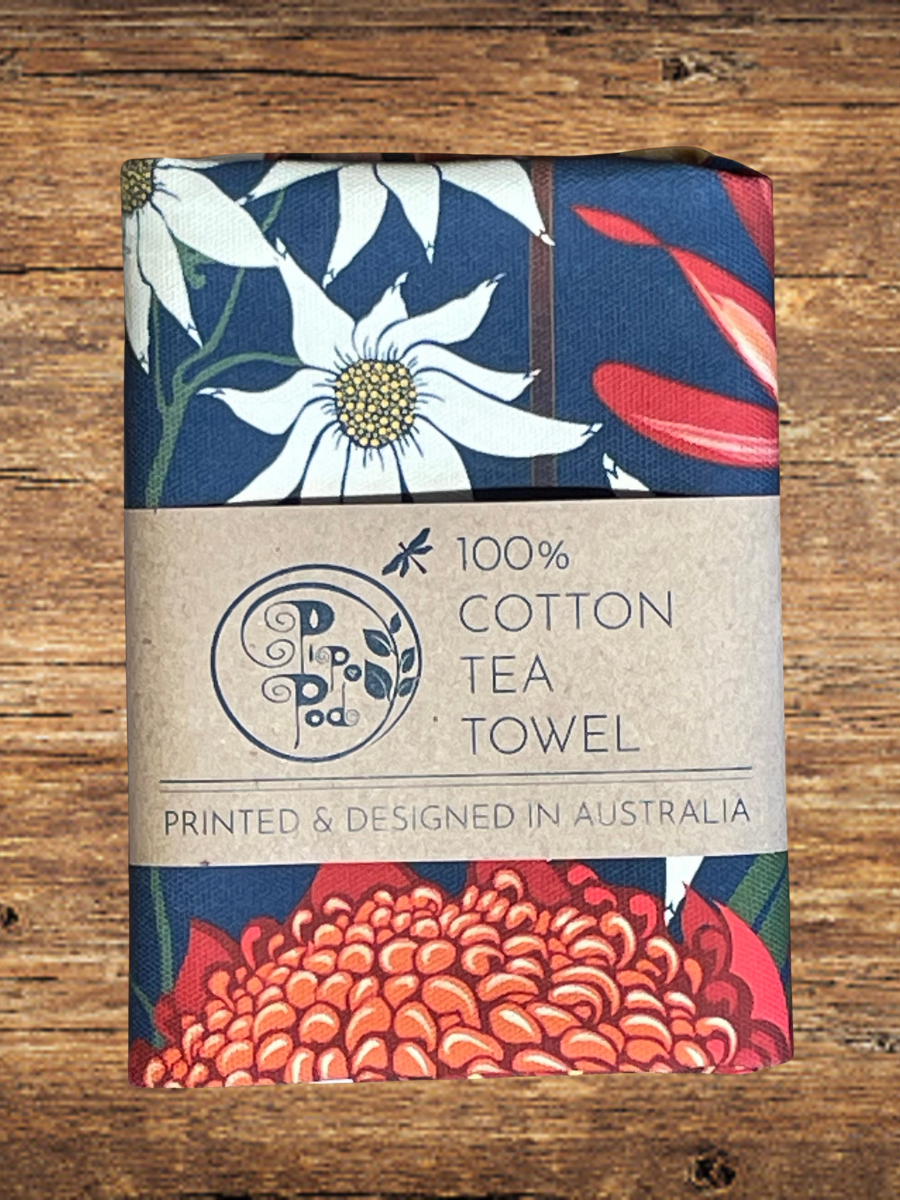 Floral patterned tea towel with branding on a wooden surface
